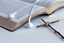 cross made of sticks and earbuds on the pages of a Bible 
