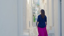 Female tourist exploring and walking in the streets of Chora, Mykonos, Greece.