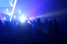 hands raised under lights at a worship service 