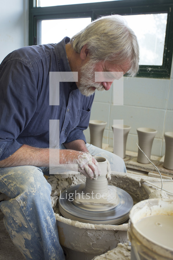 a potter shaping a tall vase 