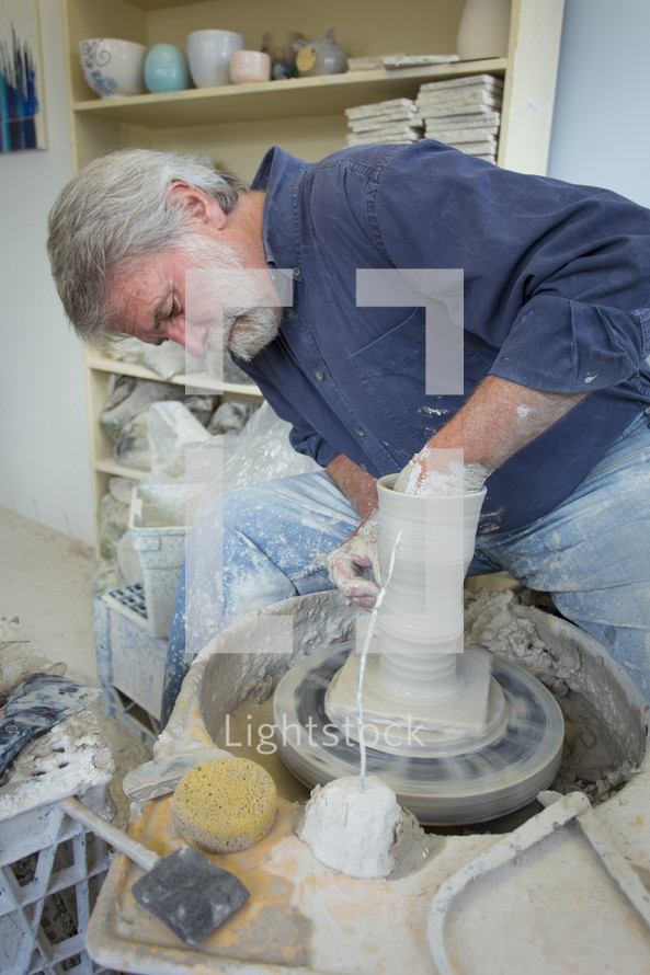 a potter shaping a tall vase 