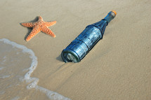 bottle and sea star on a beach 