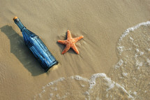 sea star and bottle on a beach 