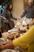 family holding hands in prayer around a Thanksgiving dinner table 