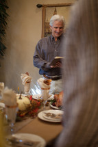 Man reading a Bible verse in prayer at a Thanksgiving table 