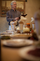 man reading a Bible at a Thanksgiving dinner table 