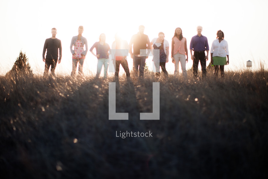 group of people in a row standing outdoors in sunlight 