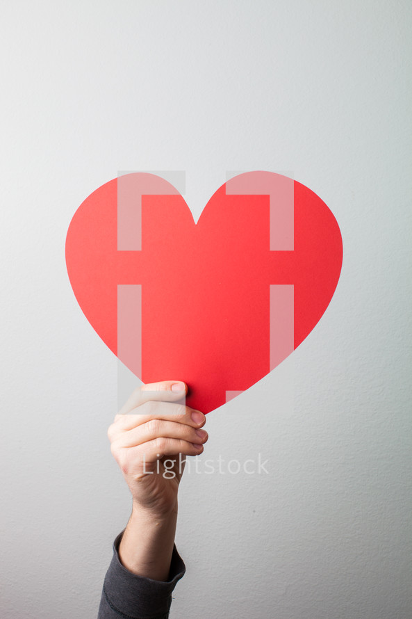 arm holding a large red paper heart