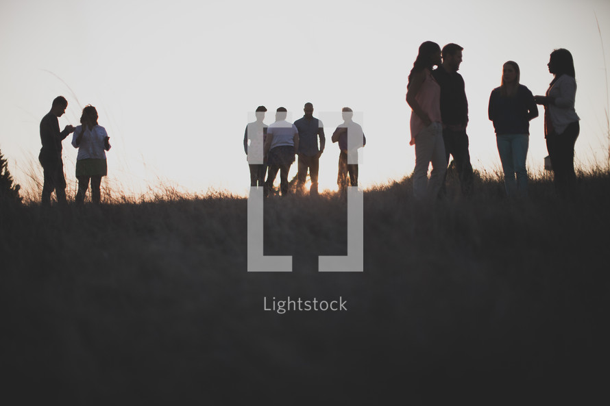 group gathered talking outdoors in a field at sunset 