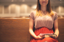 woman holding a Bible sitting in a church pew