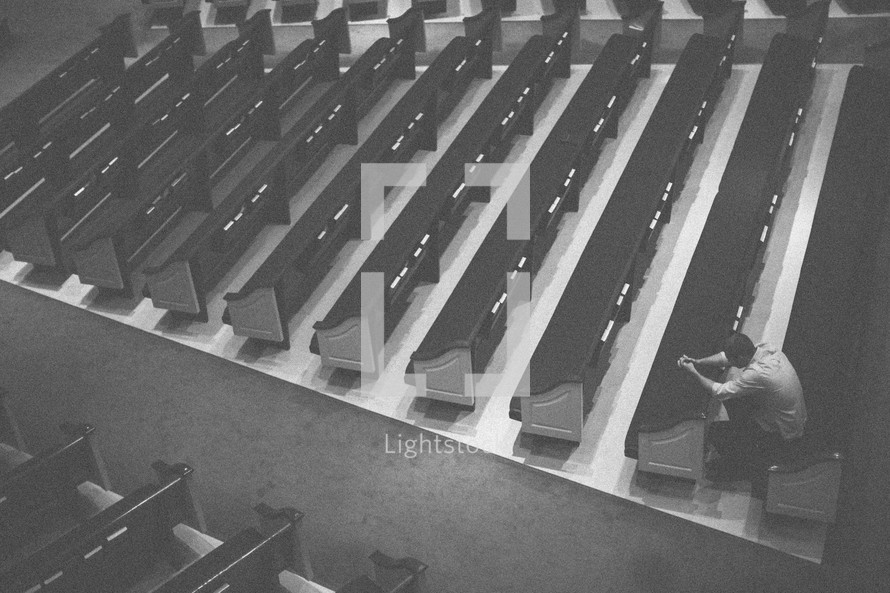man alone in prayer in an empty church