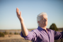 a man with raised arms standing outdoors 