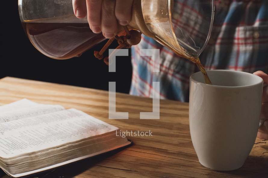 A man pouring coffee from a carafe into a coffee cup.