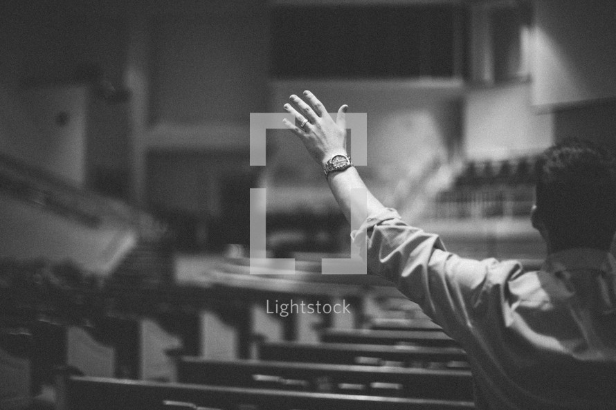 hands raised in worship to God inside an empty church