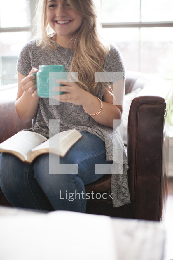 woman drinking coffee and reading a Bible in her lap 