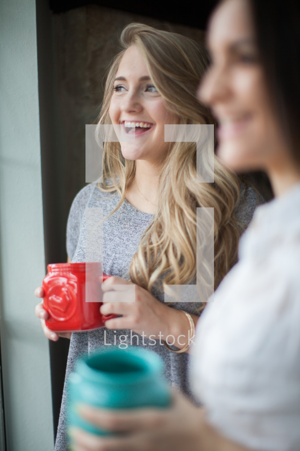 women in conversation drinking coffee at a window 