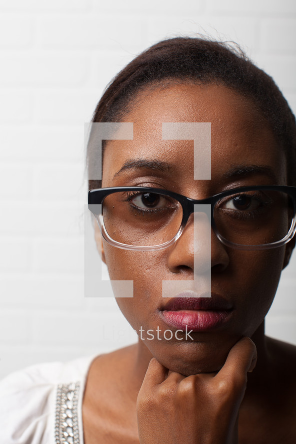stoic face of an African-American woman with reading glasses 