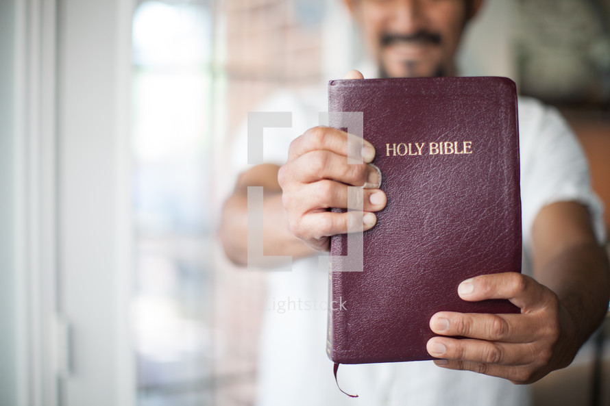A man holding a Bible out in front of him.
