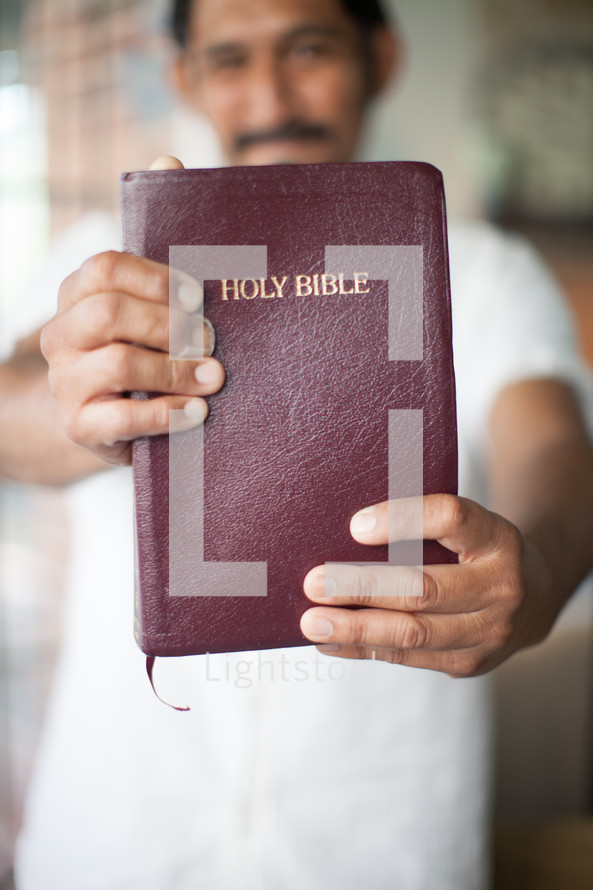 latino man holding up a Bible 