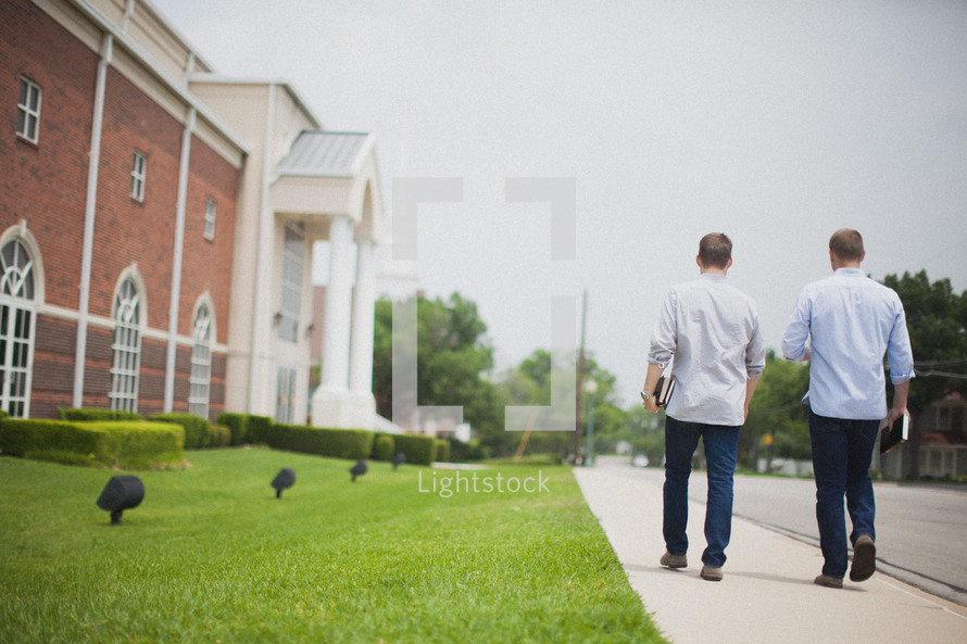 men walking down a sidewalk towards a church Sunday morning 