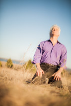 a man kneeling in prayer outdoors 