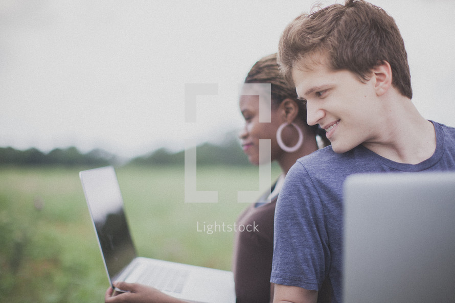 man and woman on laptops outdoors