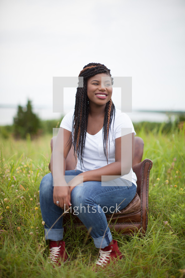 smiling woman sitting in a chair in a field 