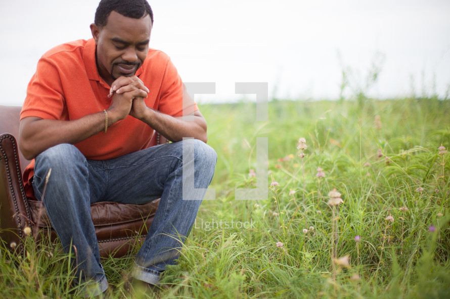 man sitting in a chair outdoors in prayer 