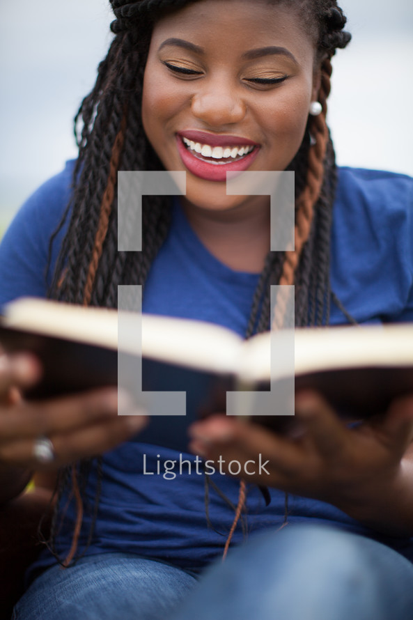 joyful African-American woman reading a Bible 