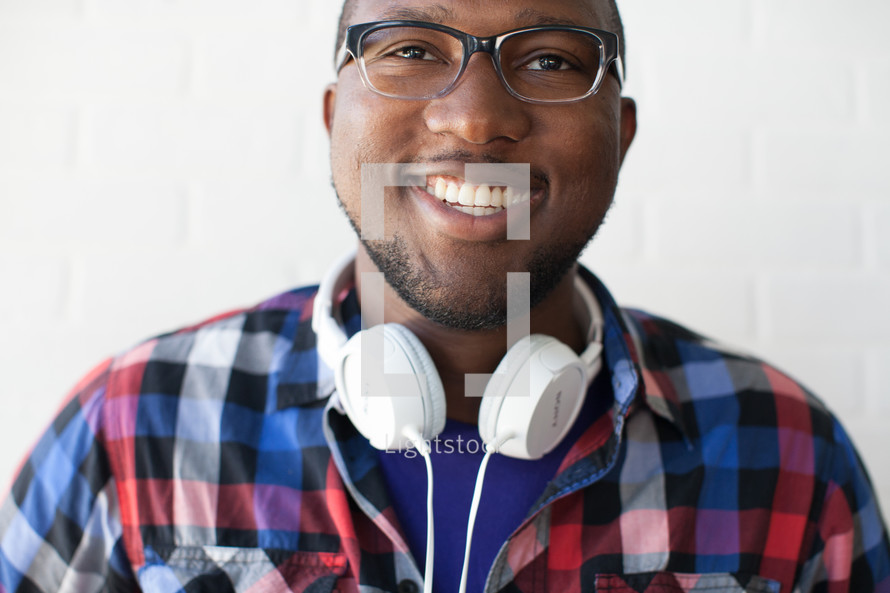 face of a man wearing reading glasses and headphones around his neck with a beard 