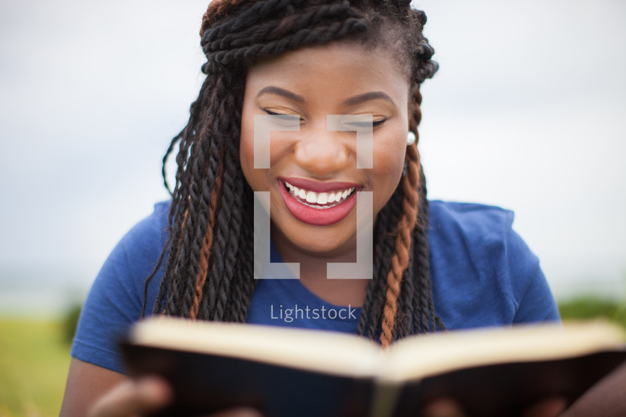 woman reading a Bible outdoors smiling 