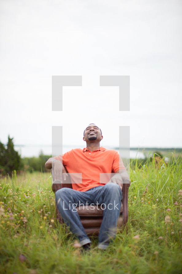 man sitting in a chair in a field relaxing 