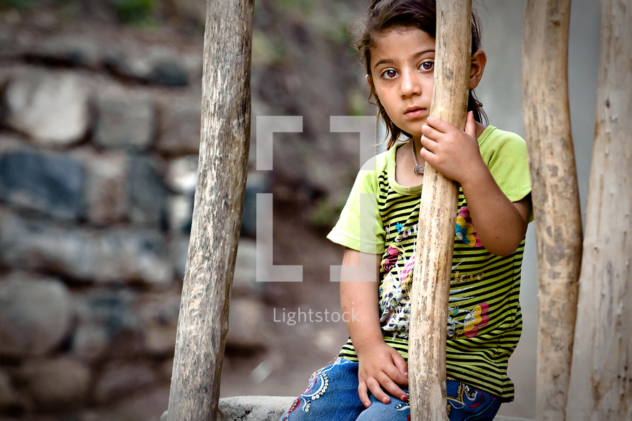 Young girl sitting behind wooden branches