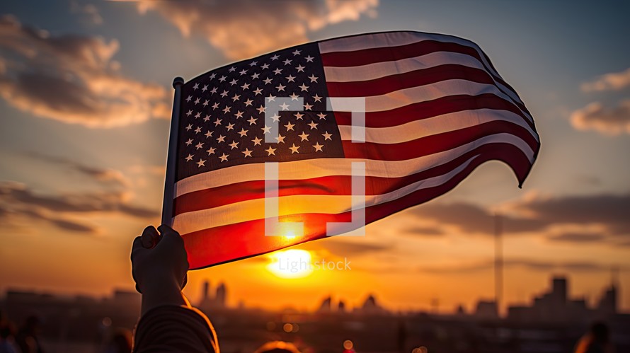 American flag in the hand of a man against the background of the sunset