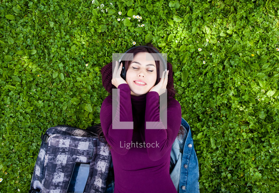 young woman listening music with headphones in outdoor.
