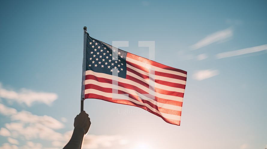 American flag in hand on blue sky background. United States of America.