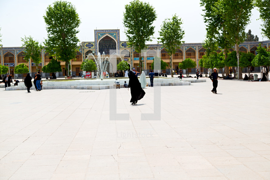 people walking through a courtyard towards a mosque in Iran 