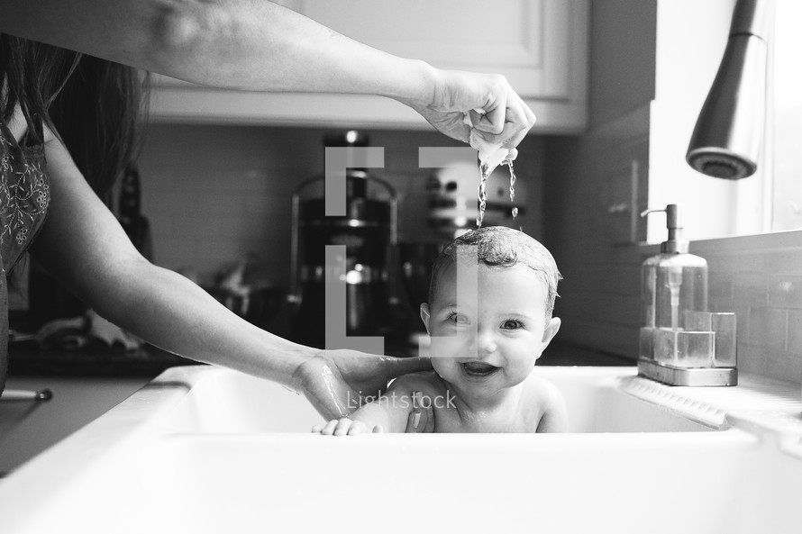 baby getting bathed in a sink 