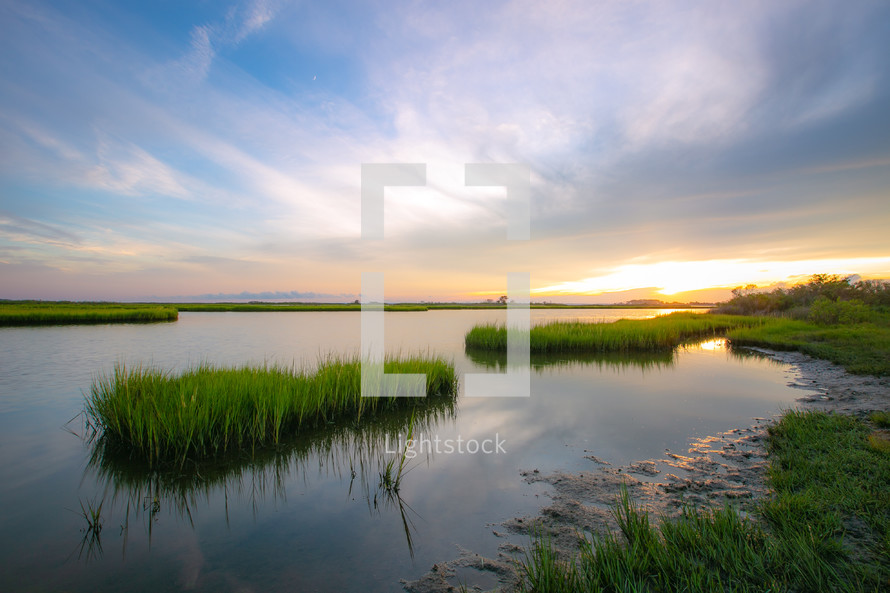 Sunset reflection with marsh grass waterway on the coast 
