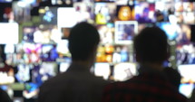 Defocused shot of two people standing in front of a virtual wall with moving pictures.