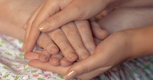 Close-up shot of young female hands holding and stroking hands of an elderly woman.