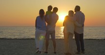 Family looking at golden sunset over the sea