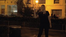 Woman trying to throw the bottle into street trash can
