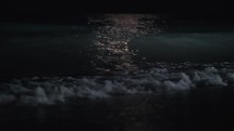 Slow motion shot of dark waves washing the seashore at night