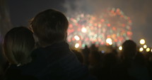 Back of a mother holding her son while watching fireworks.