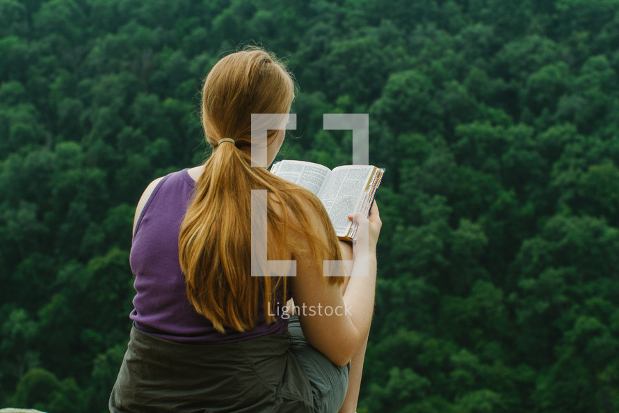 woman reading a Bible on a mountaintop 