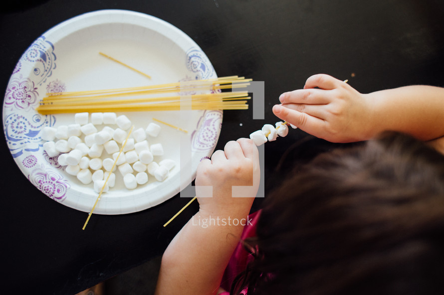 a child playing with spaghetti noodles and marshmallows to improve motor function 