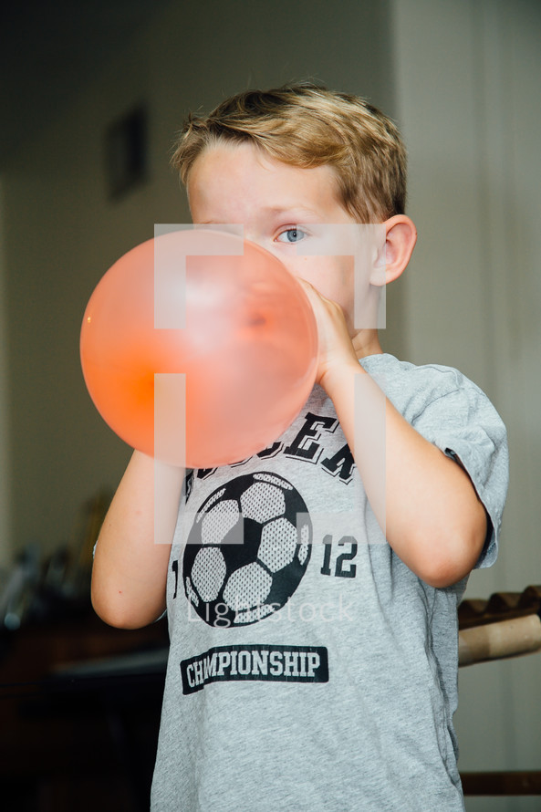 a boy child blowing up a balloon 