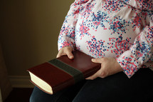a pregnant woman holding a Bible 