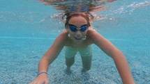 Boy in goggles swimming toward the camera in the ocean